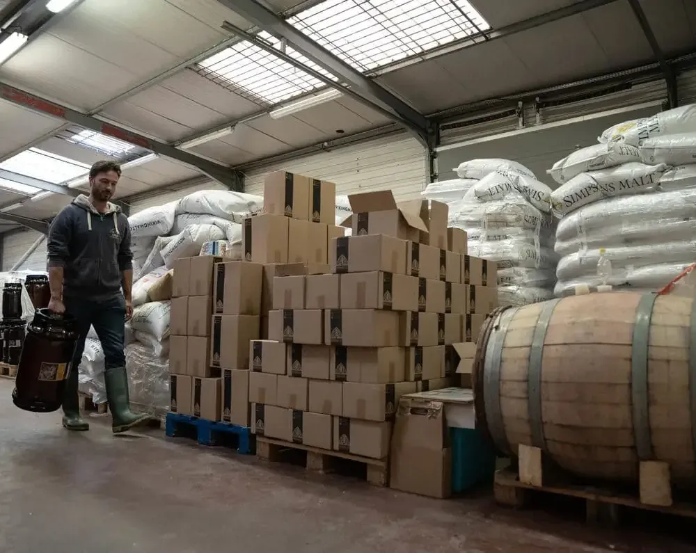 Un brasseur d’Arcka Brewing Co dans l’entrepôt, entre cartons et fûts.